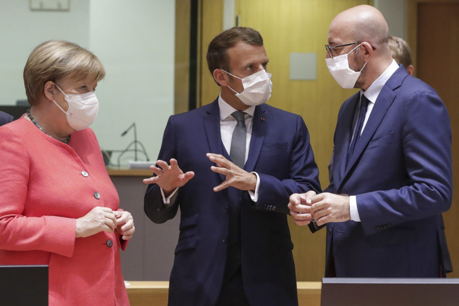 European Council President Charles Michel, right, speaks with French President Emmanuel Macron, center, and German Chancellor Angela Merkel during a round table meeting at an EU summit in Brussels, Friday, July 17, 2020 (Stephanie Lecocq, Pool Photo via AP).